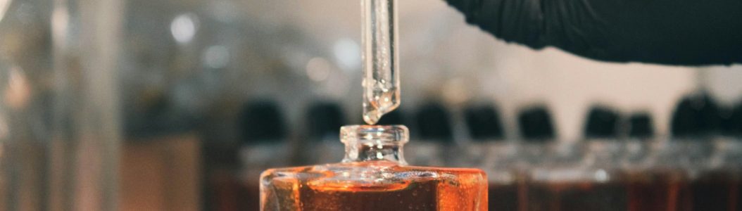 © Fulvio Ciccolo/Unsplash (A person in a lab coat is holding a test tube with liquid in it.)